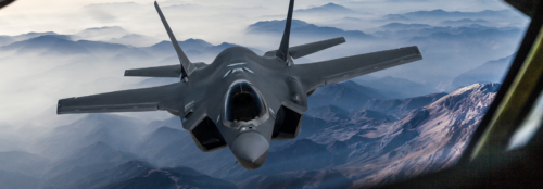 grey jet taking off in the sky with landing gear still visible